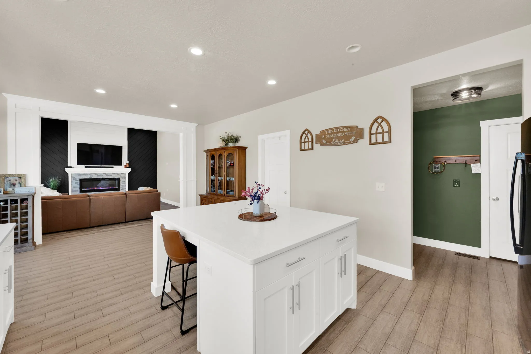 Open concept living area featuring a kitchen island with white cabinetry and a light-toned countertop
