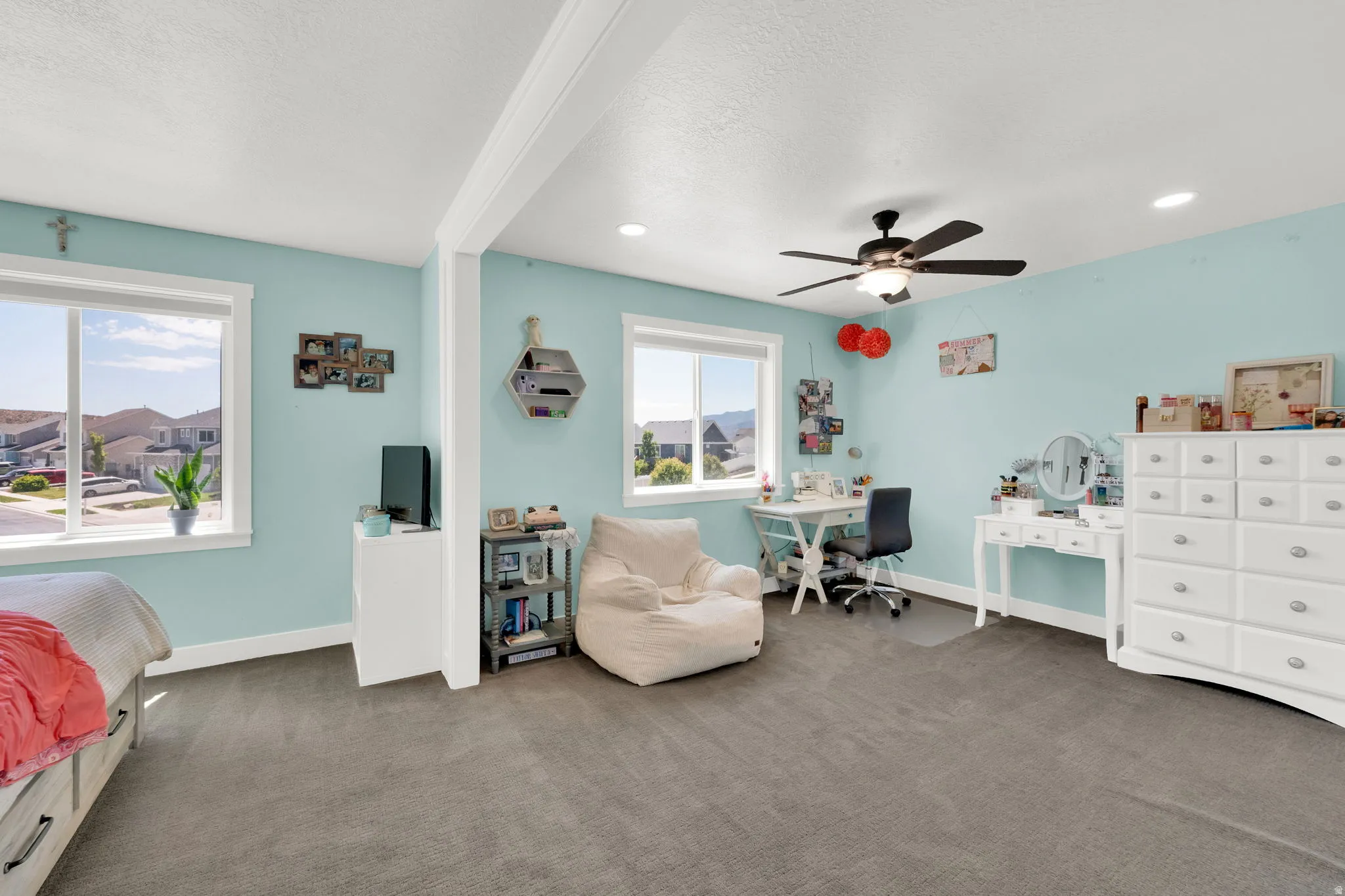Spacious room featuring carpeting, two large windows with white trim, a ceiling fan, and recessed lighting