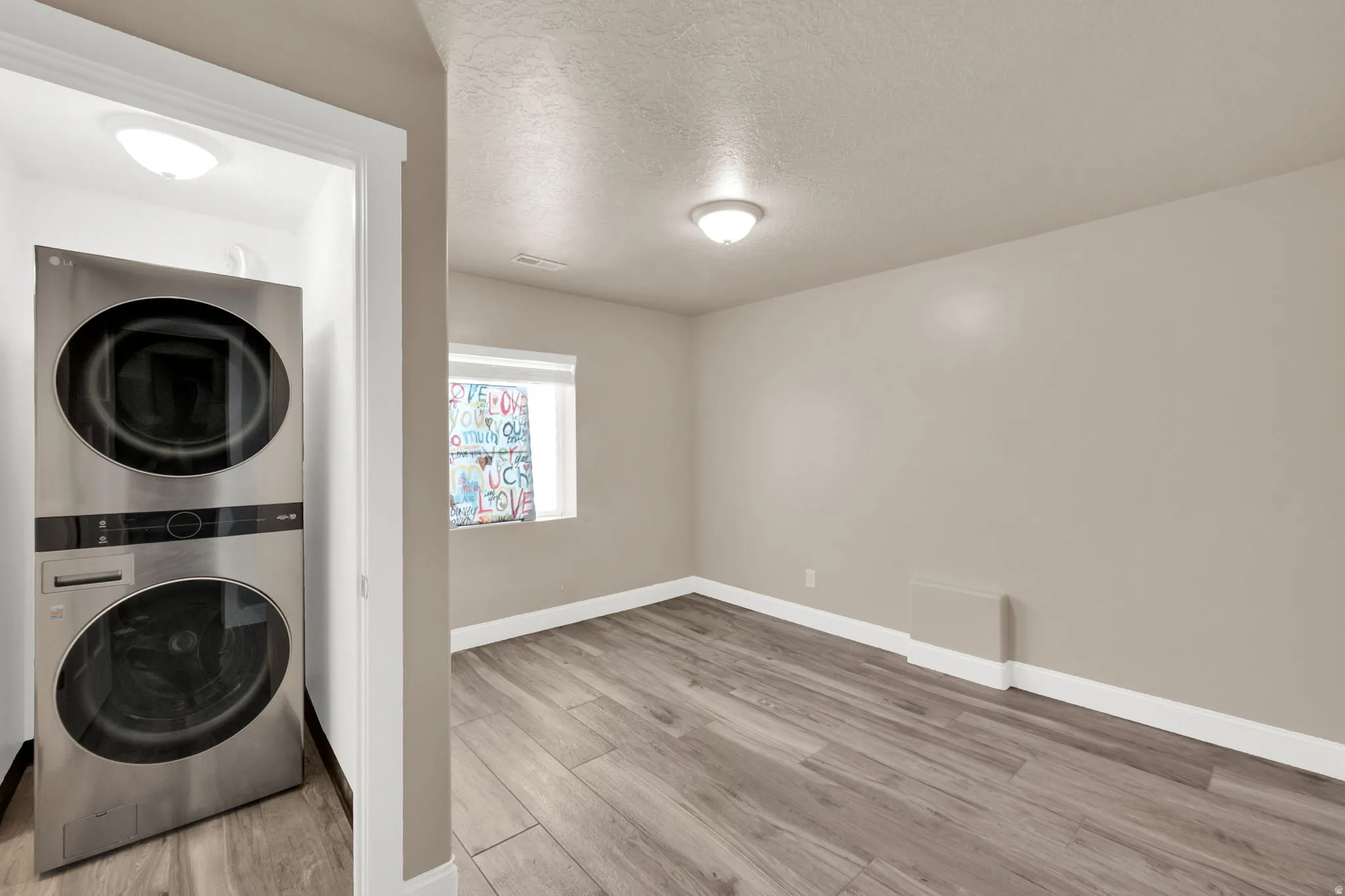 Dedicated laundry area featuring a stacked washer and dryer unit