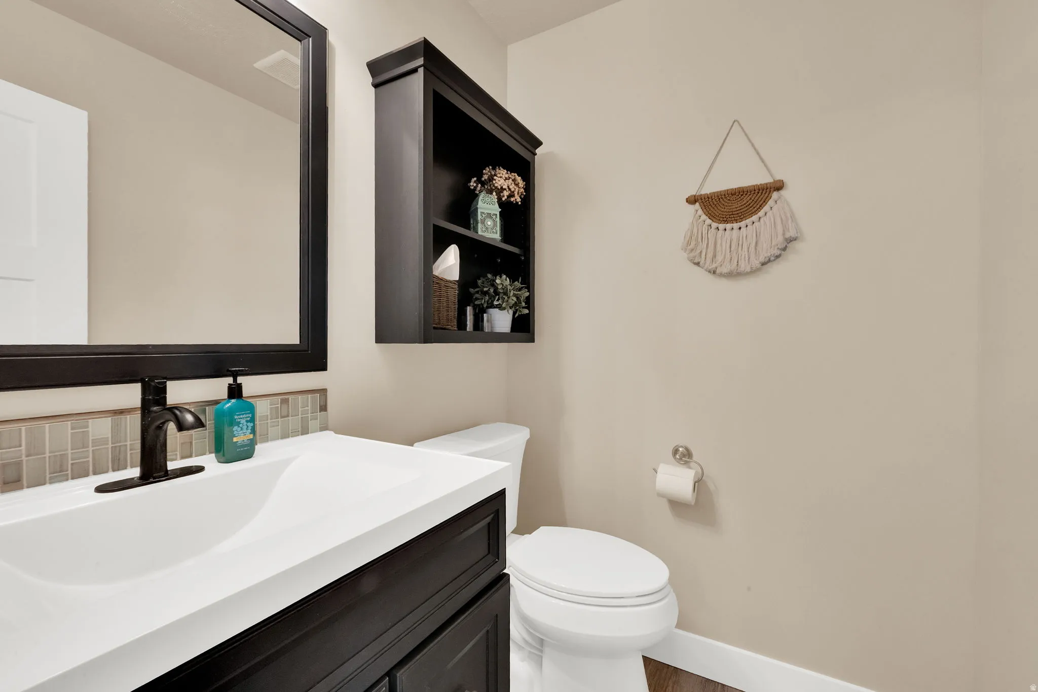 Bathroom featuring a dark wood-finish vanity with an integrated white sink, a matte black faucet, and a rectangular mirror
