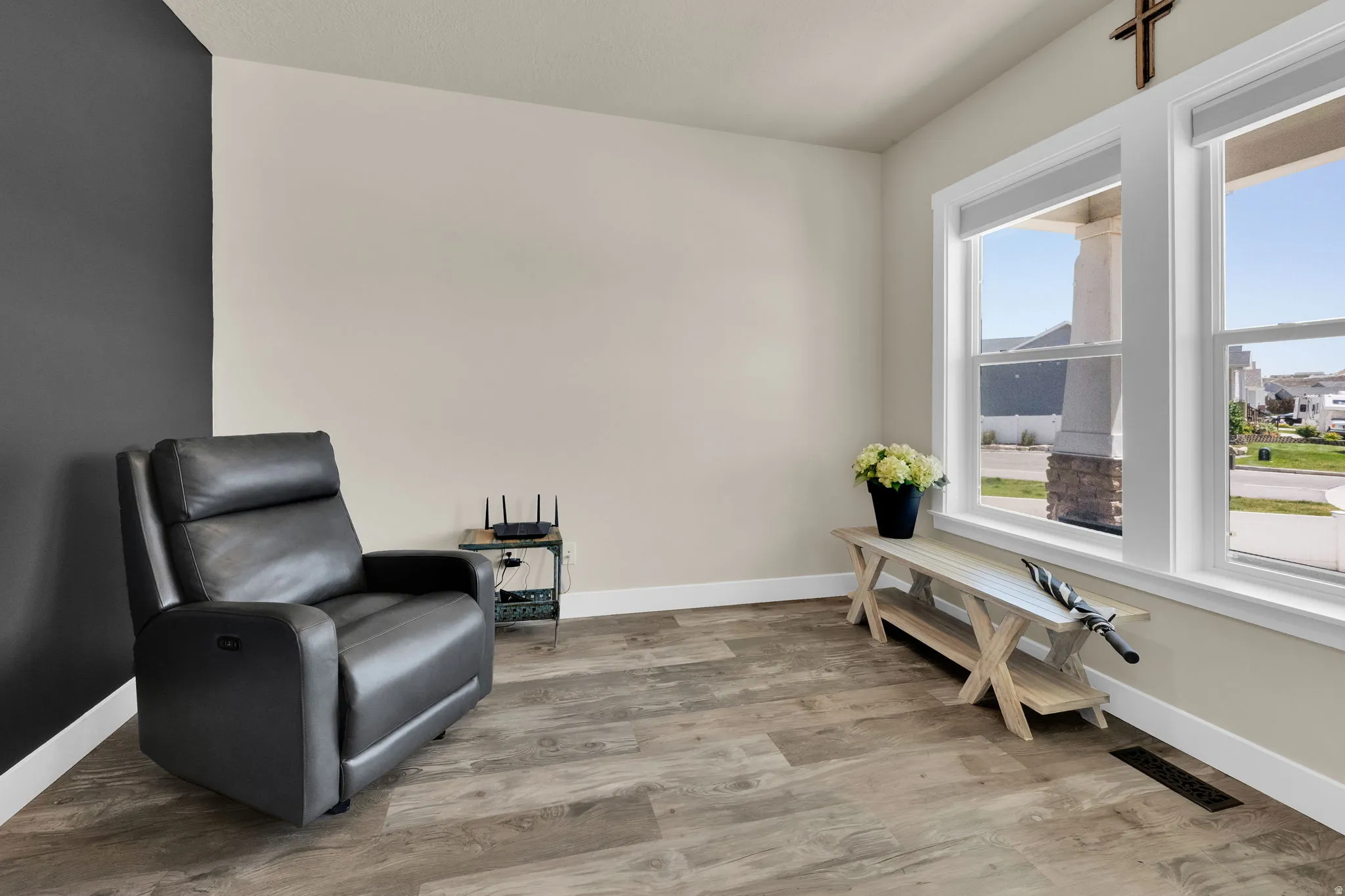 Home office featuring wood-finish flooring, tall baseboards, and a neutral color palette with an accent wall