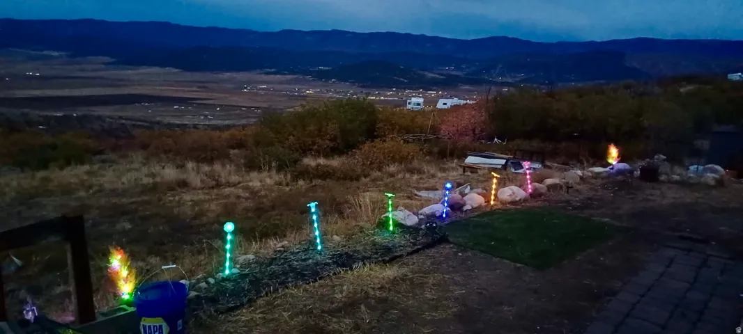 Expansive outdoor space featuring a paved patio area, landscape lighting, and natural terrain with distant mountain scenery