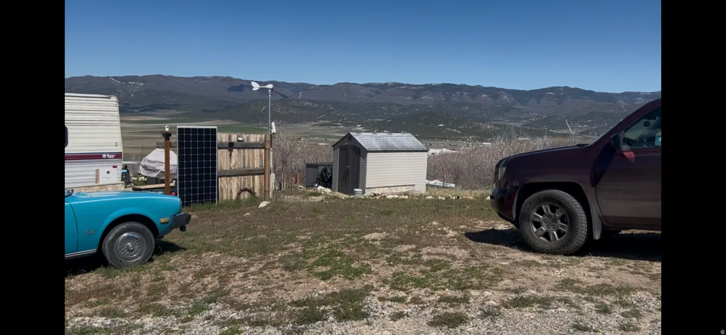 Expansive outdoor area featuring a storage shed, solar panels, and a wind turbine
