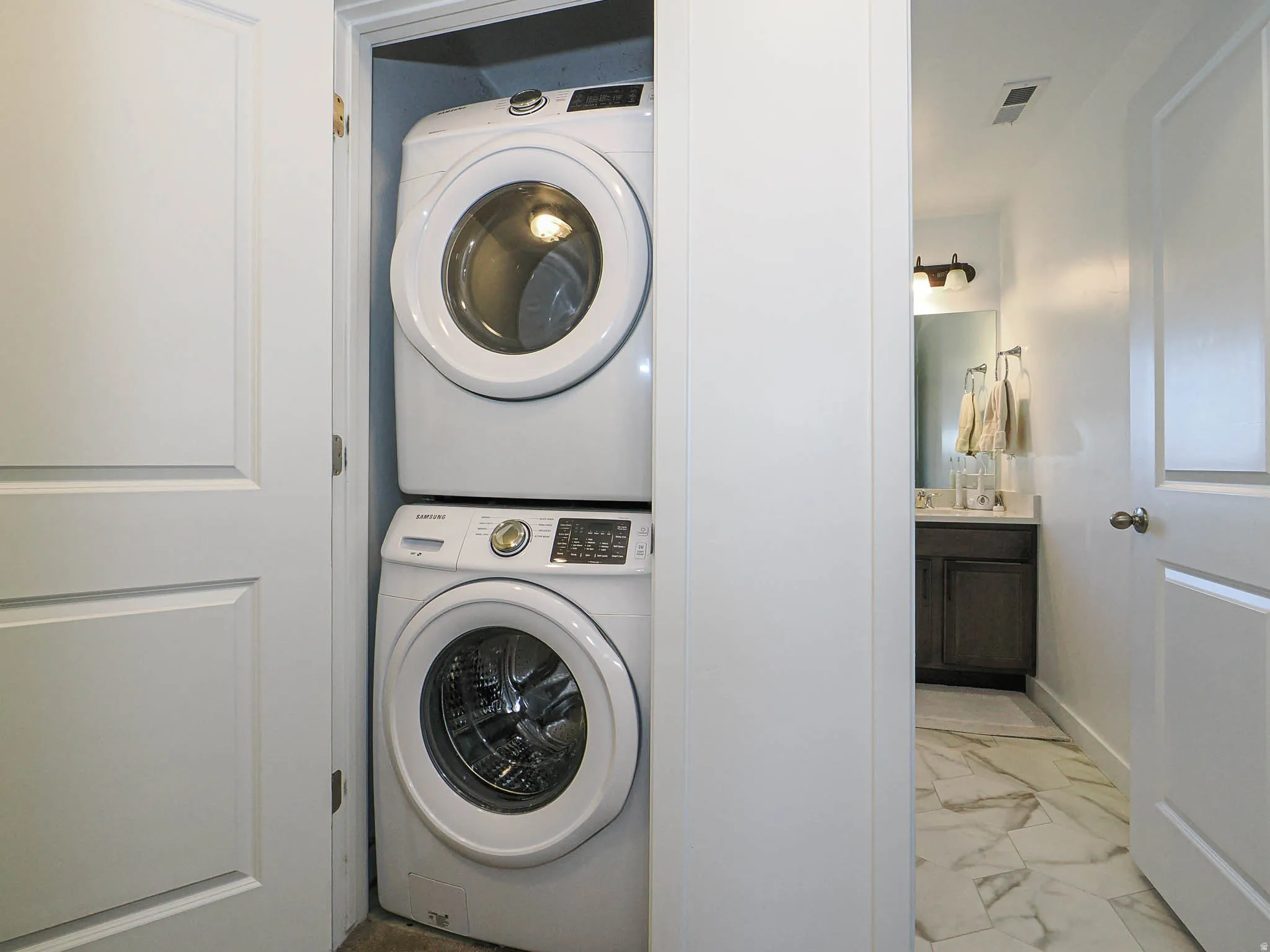 White stackable washer and dryer unit in a dedicated alcove