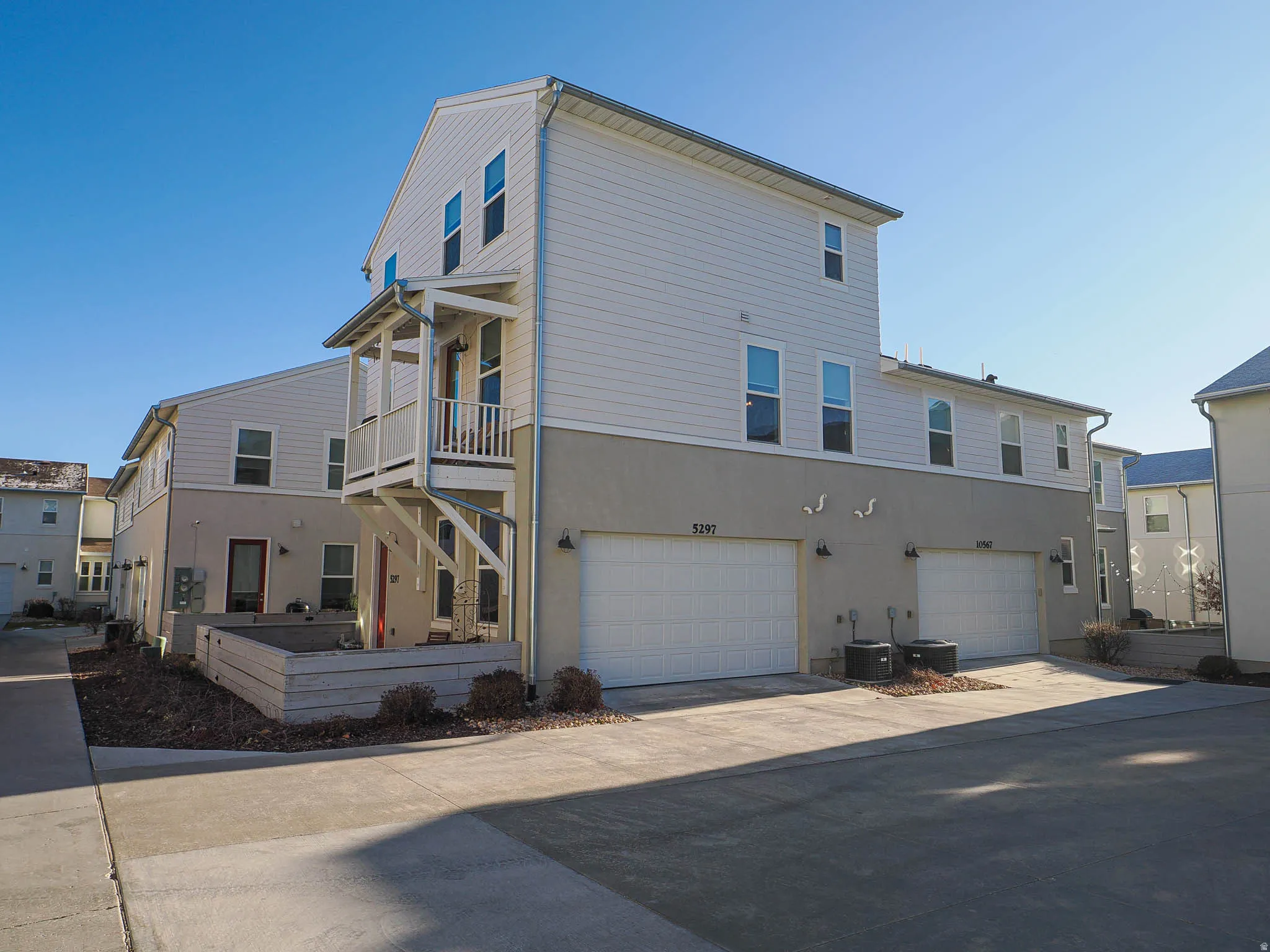 Contemporary multi-level exterior featuring white siding, a stucco base, and multiple windows