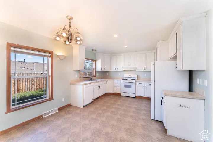 Kitchen featuring white cabinetry, solid-surface countertops, tile flooring, and a multi-arm chandelier