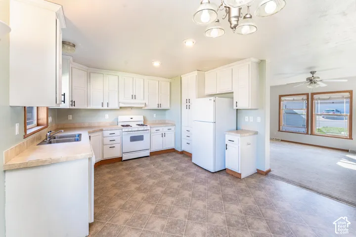Kitchen featuring white cabinetry with dark hardware, laminate countertops, a stainless steel double-basin sink, a white range, and tiled flooring