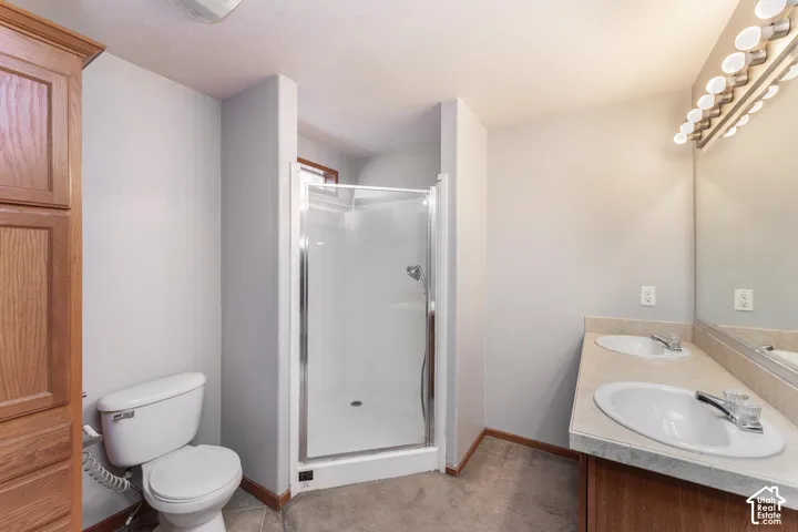 Dual-sink vanity with a solid-surface countertop, full-width mirror, glass-enclosed shower, and built-in vertical cabinetry