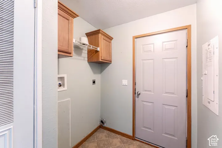 Laundry area featuring wood-finish cabinetry, wire shelving, tile flooring, and a six-panel door