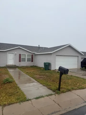 Single-story residence featuring light gray horizontal siding, an attached garage with a white door, and a gray shingle roof