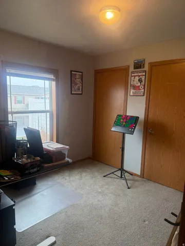 Carpeted room featuring a window with wood trim, two wood-finish doors, and a ceiling-mounted light fixture