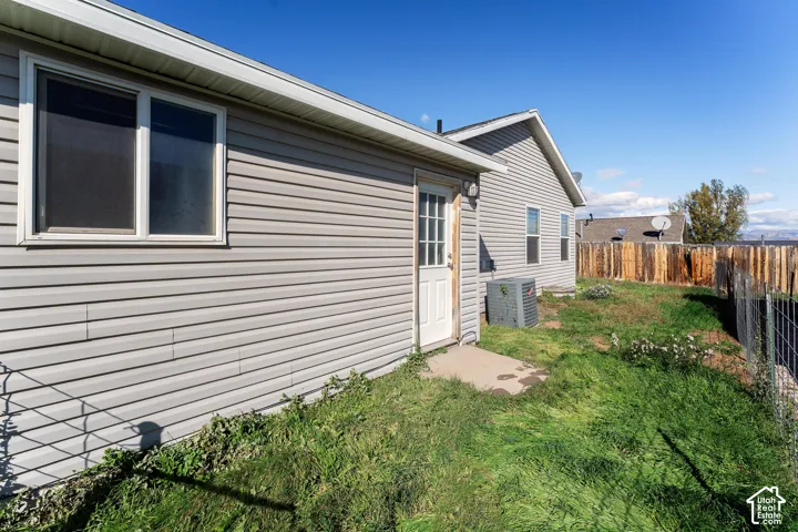 Exterior features include horizontal siding, a white-framed pedestrian door, vinyl-framed windows, and a concrete stoop