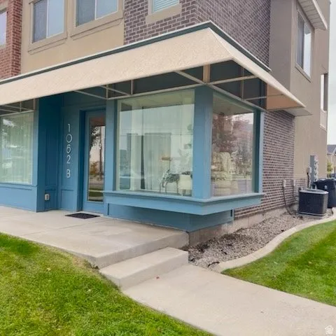 Contemporary exterior featuring a large bay window, an inviting entryway, a light-colored awning, and a brick facade