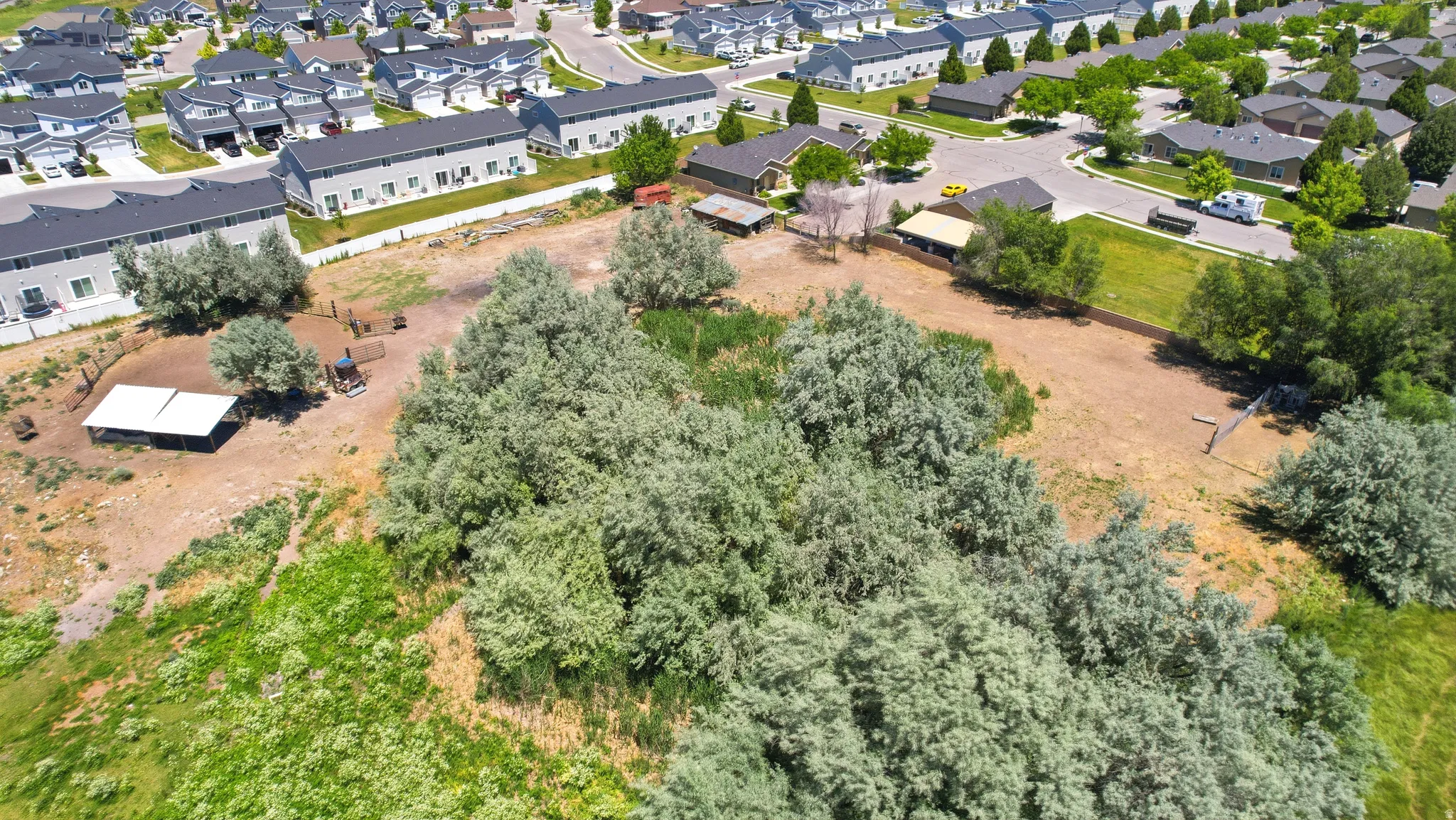 Expansive lot featuring mature trees and open land, bordered by residential development