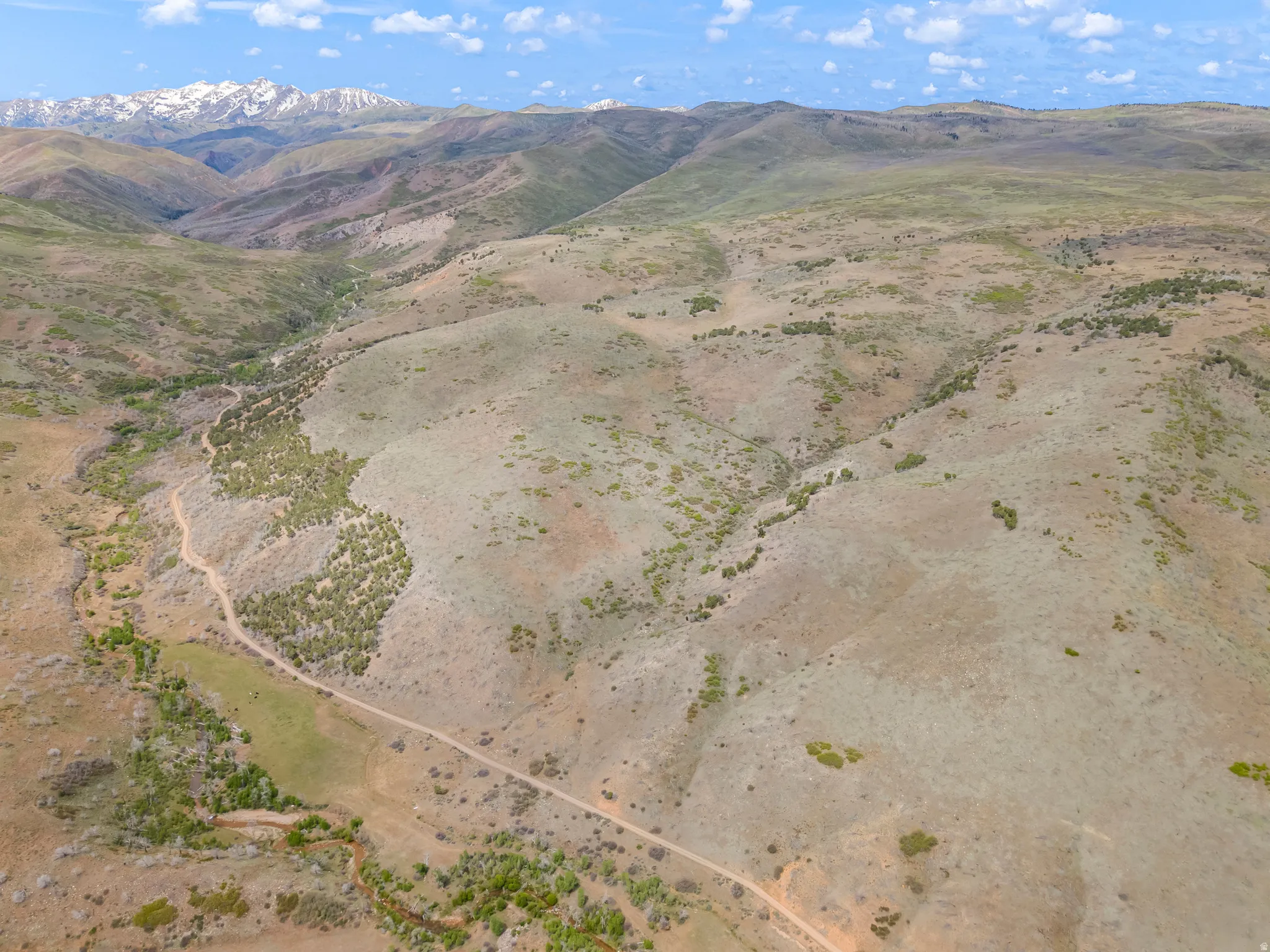 Expansive mountain landscape featuring varied topography, natural vegetation, and a winding unpaved road
