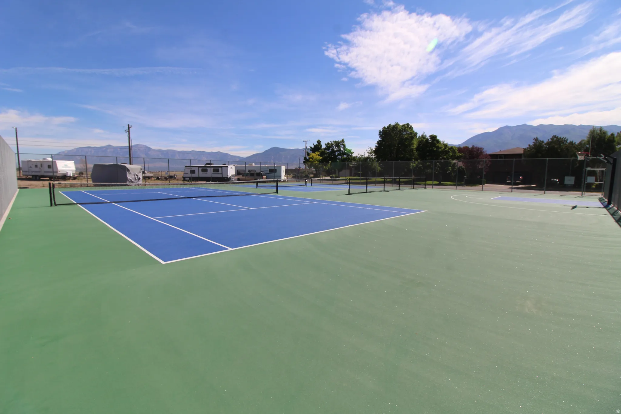 Recreational area featuring two full-size pickleball courts with blue and green surfacing, white line markings, and a black net