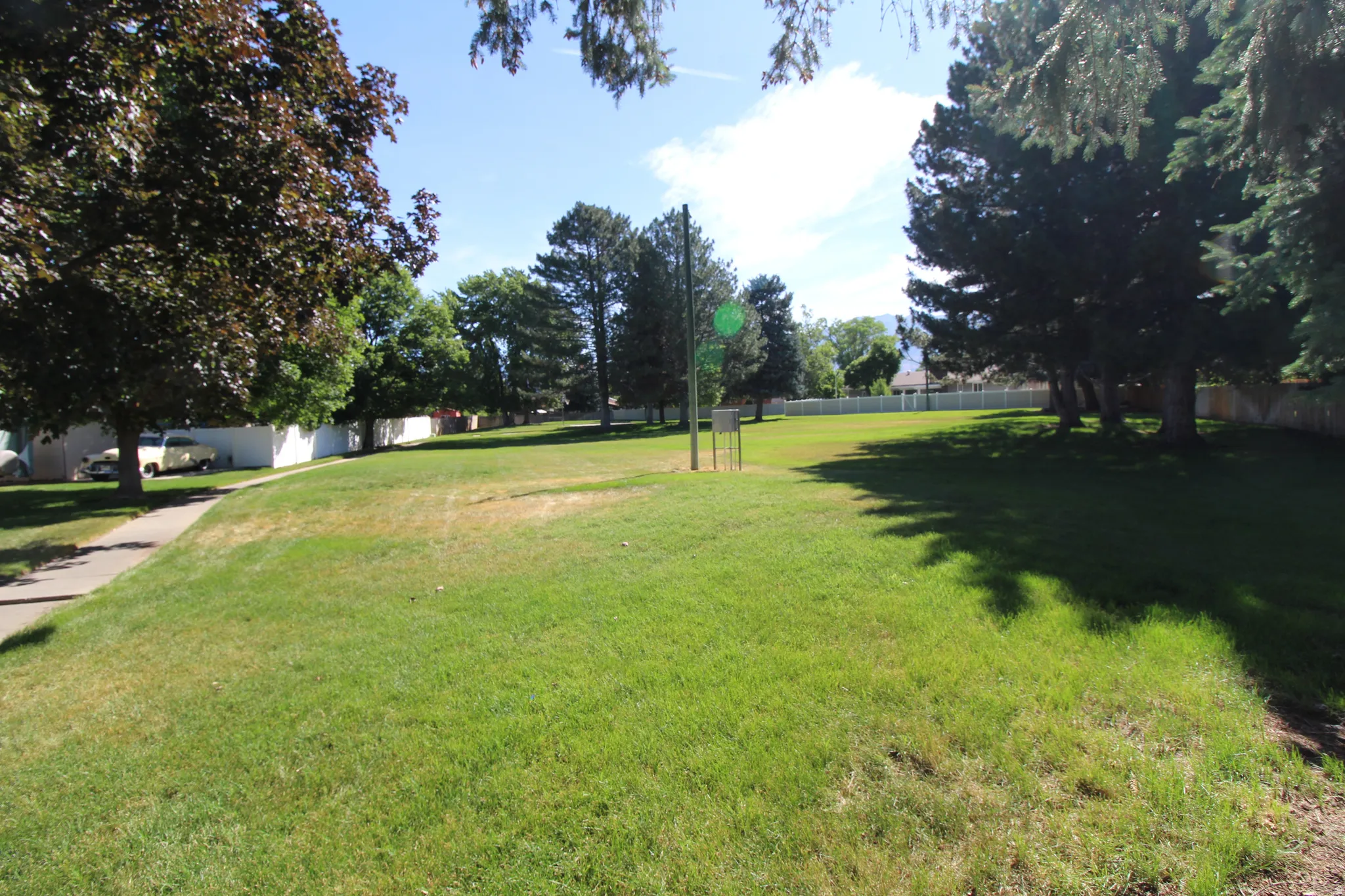 Expansive green space featuring a park with mature trees and a paved walkway