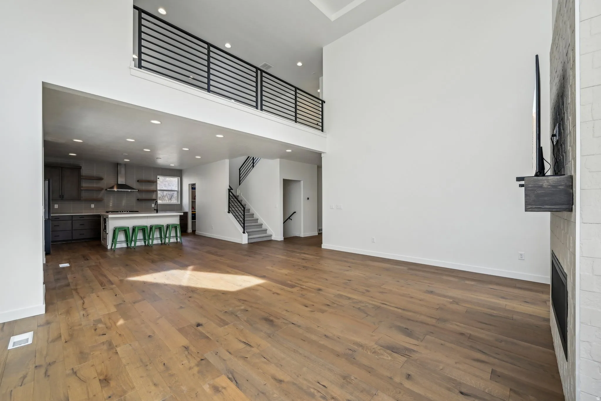Spacious living area featuring wood-finish flooring, a built-in fireplace with a hearth, and high ceilings