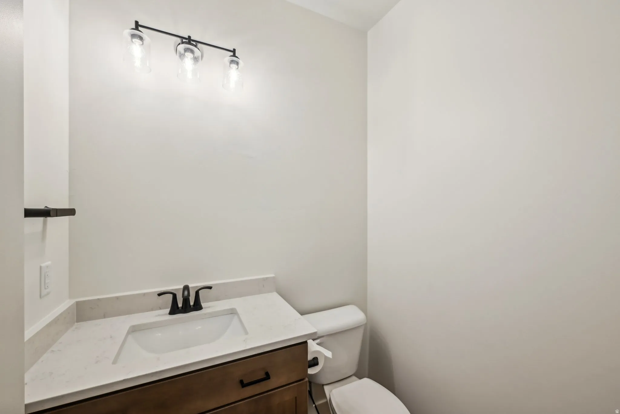 Modern vanity featuring a white rectangular under-mount sink, black faucet, and light-toned countertop