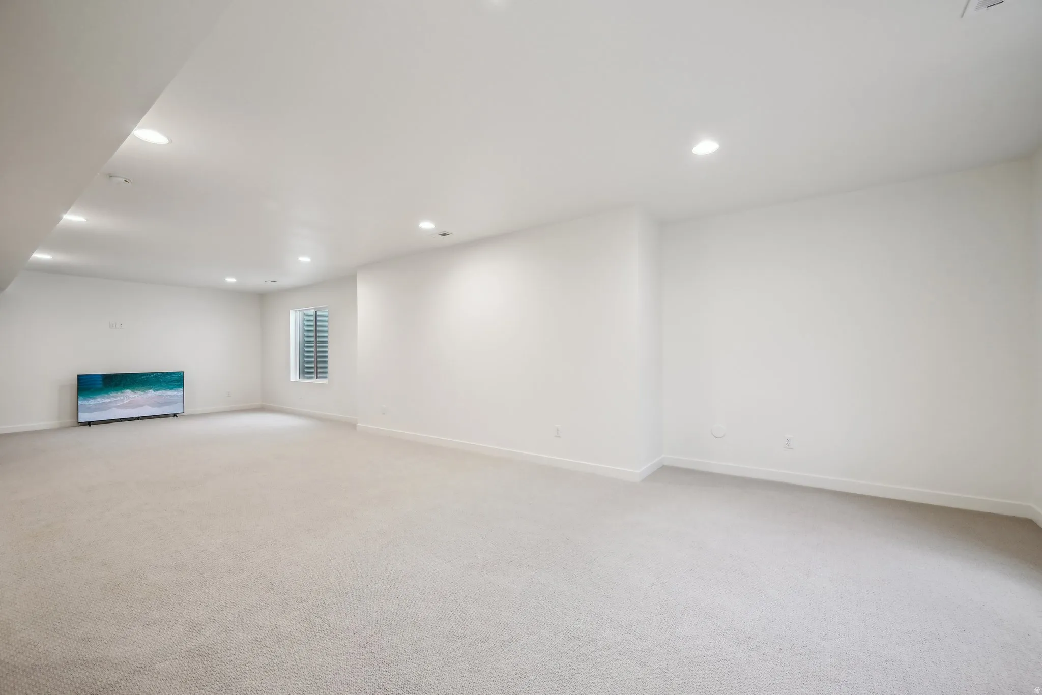 Spacious carpeted room featuring recessed lighting, a single window with blinds, and ample wall space