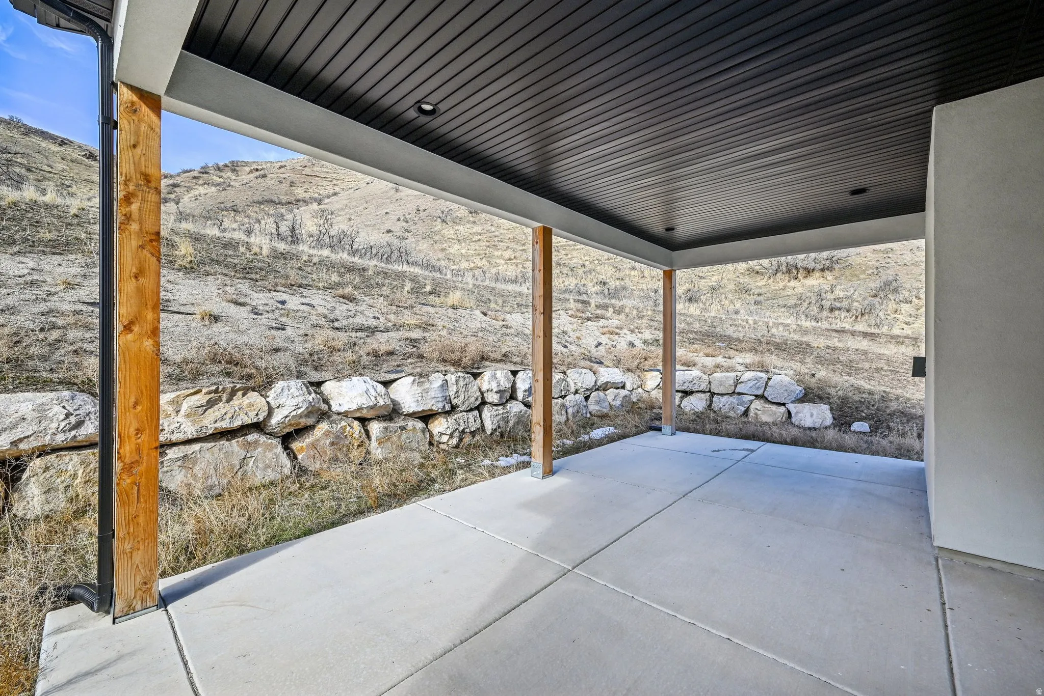 Covered patio featuring a concrete slab floor, recessed lighting, and a dark wood-finish ceiling