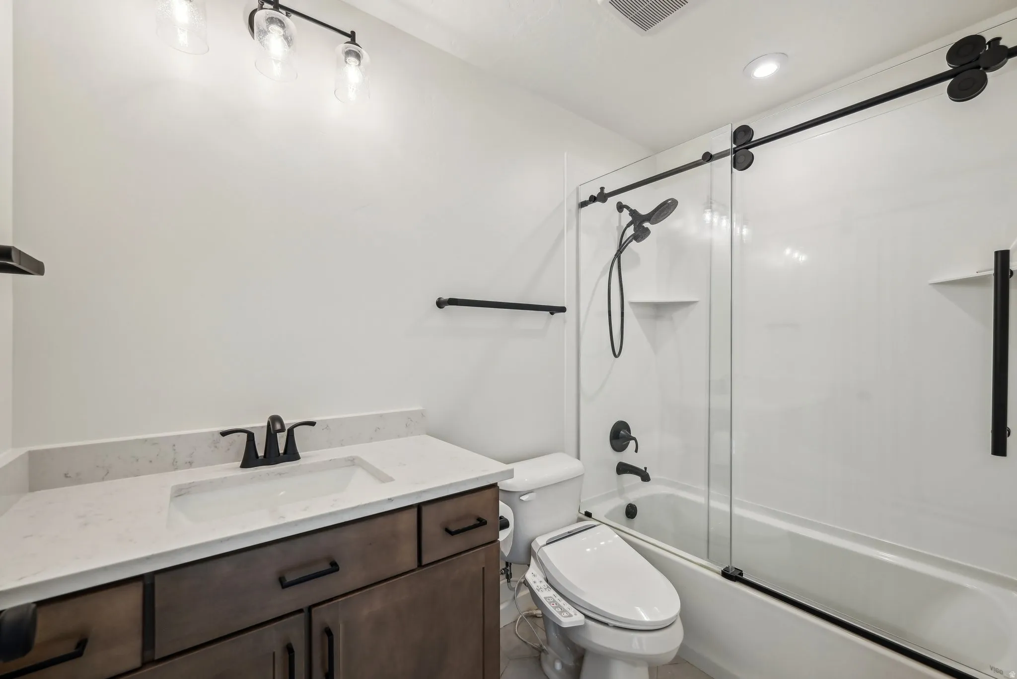 Bathroom featuring a single vanity with dark wood-finish cabinetry, a white countertop with integrated sink, and matte black fixtures