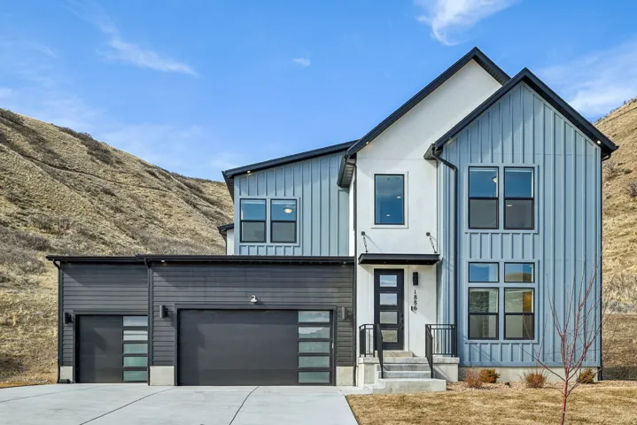 Modern mountain-side residence featuring a multi-textured facade with vertical siding and stucco finishes