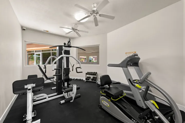 Dedicated fitness area featuring a comprehensive multi-station gym, durable rubber flooring, and two ceiling fans