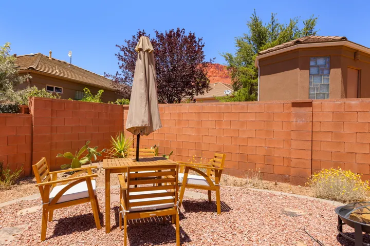 Private outdoor patio featuring a red block wall, rock ground cover, and desert landscaping