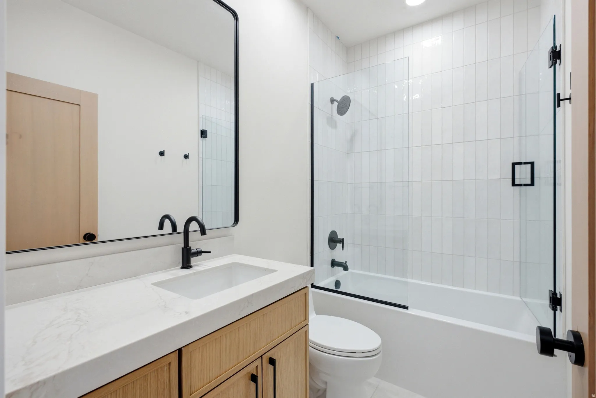 Bathroom featuring a single vanity with stone countertop, integrated sink, and matte black faucet