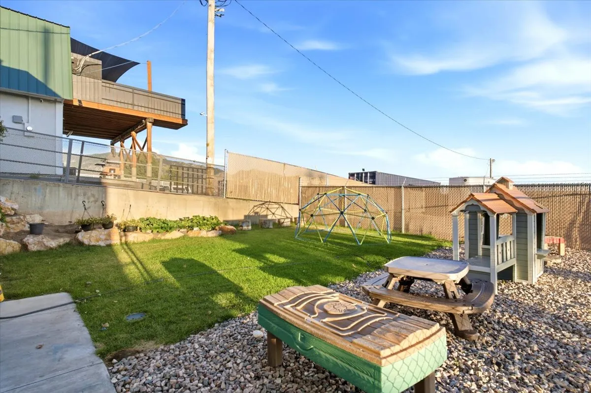 Tiered backyard featuring a manicured lawn area, a gravel section, and a raised concrete retaining wall with integrated plantings