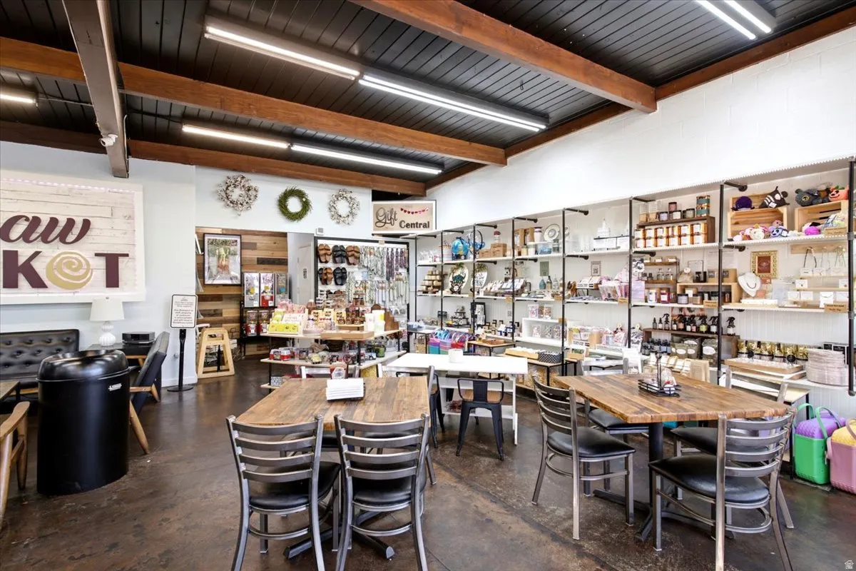 Spacious commercial interior featuring exposed wood beams, track lighting, and concrete flooring