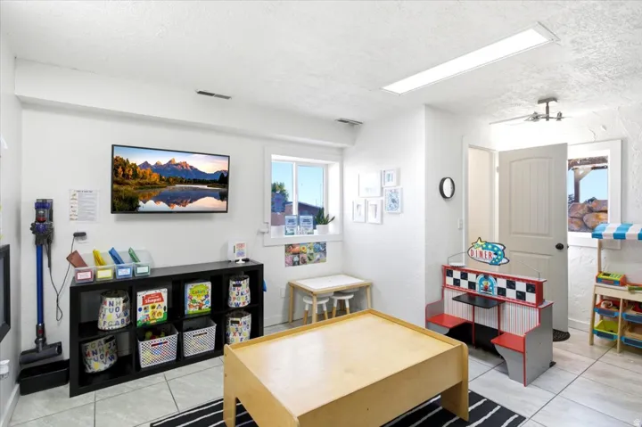 Brightly lit interior space featuring white walls and textured ceilings