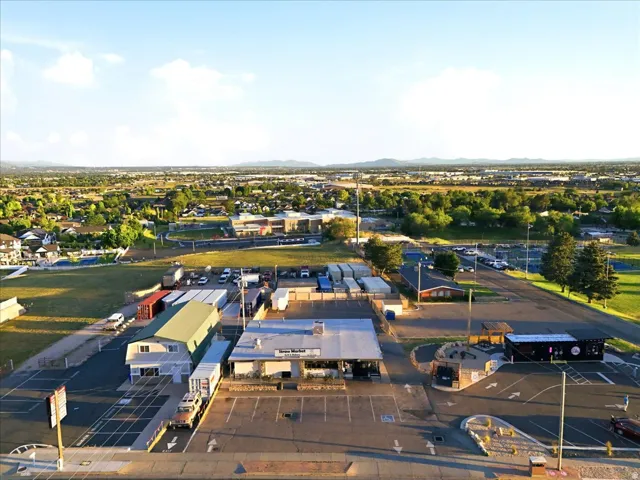 Commercial property featuring multiple buildings, expansive paved parking areas, a drive-through structure, and storage containers