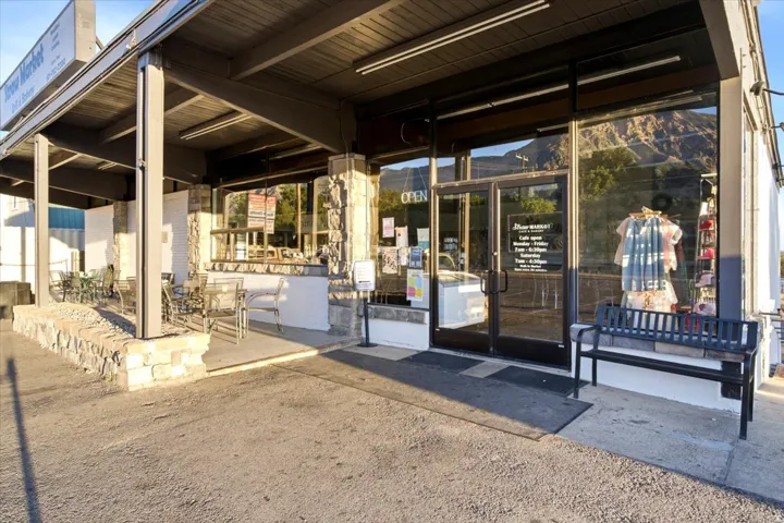 Commercial storefront featuring large display windows and a covered outdoor patio