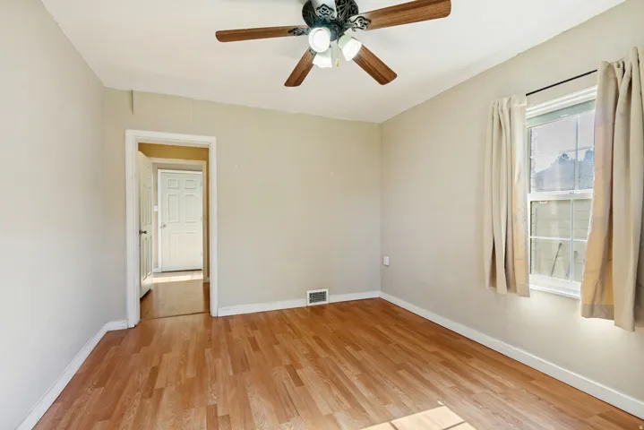 Interior room featuring wood-finish flooring, light-toned wall paint, and a ceiling fan with integrated lighting
