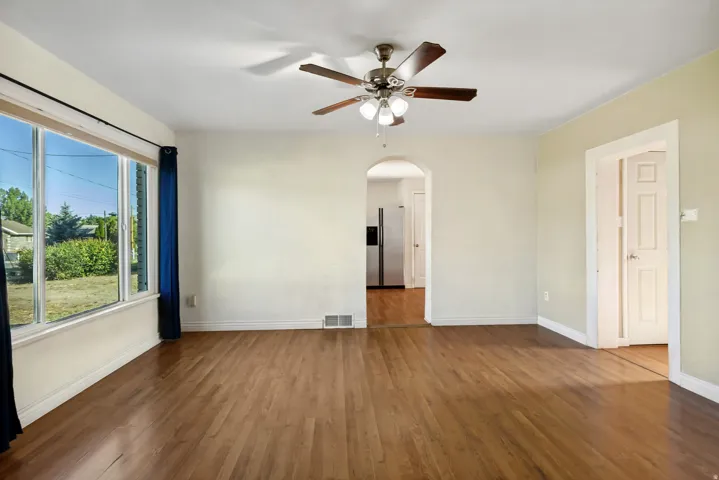 Spacious interior featuring wood-finish flooring, a large multi-pane window, and an arched doorway