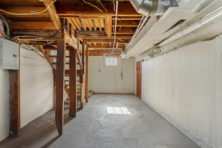Unfinished basement space featuring exposed wood joists and concrete flooring