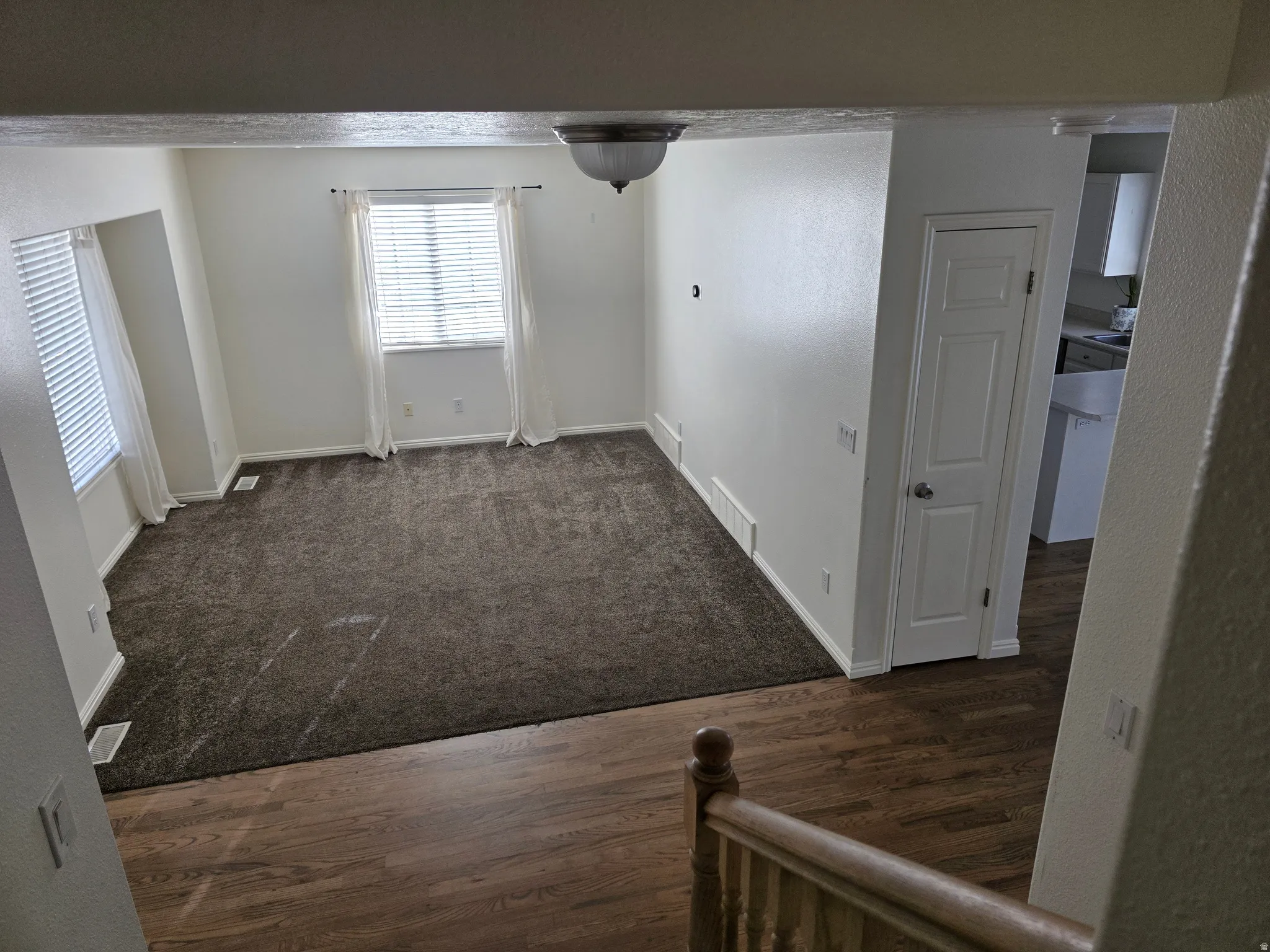 Open living area featuring neutral-toned walls and dark carpeting