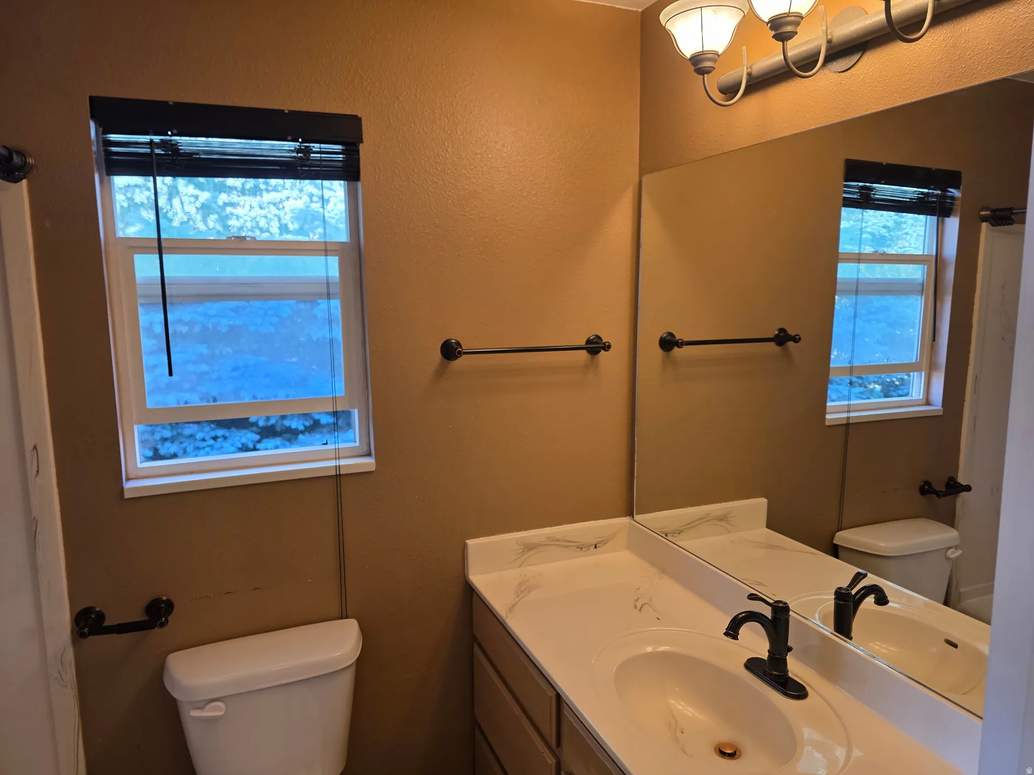 Bathroom vanity featuring a single basin sink, dark bronze faucet, and a light-toned countertop