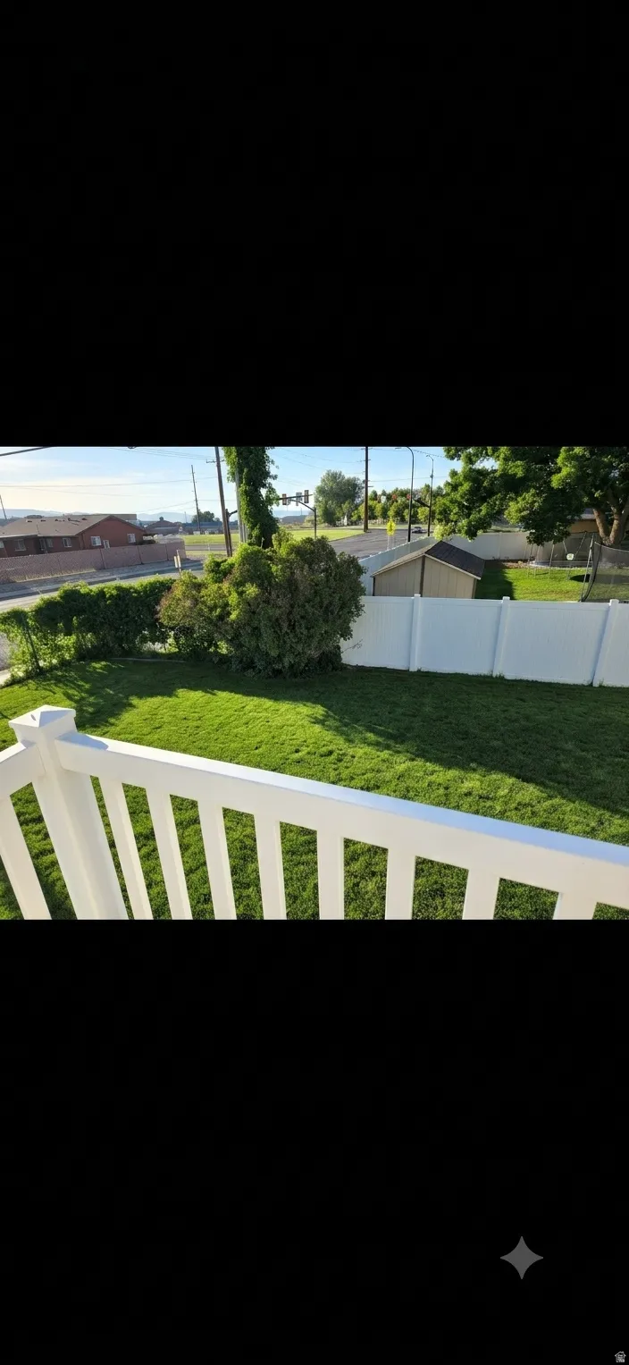 Expansive green lawn with a white vinyl fence and mature shrubbery