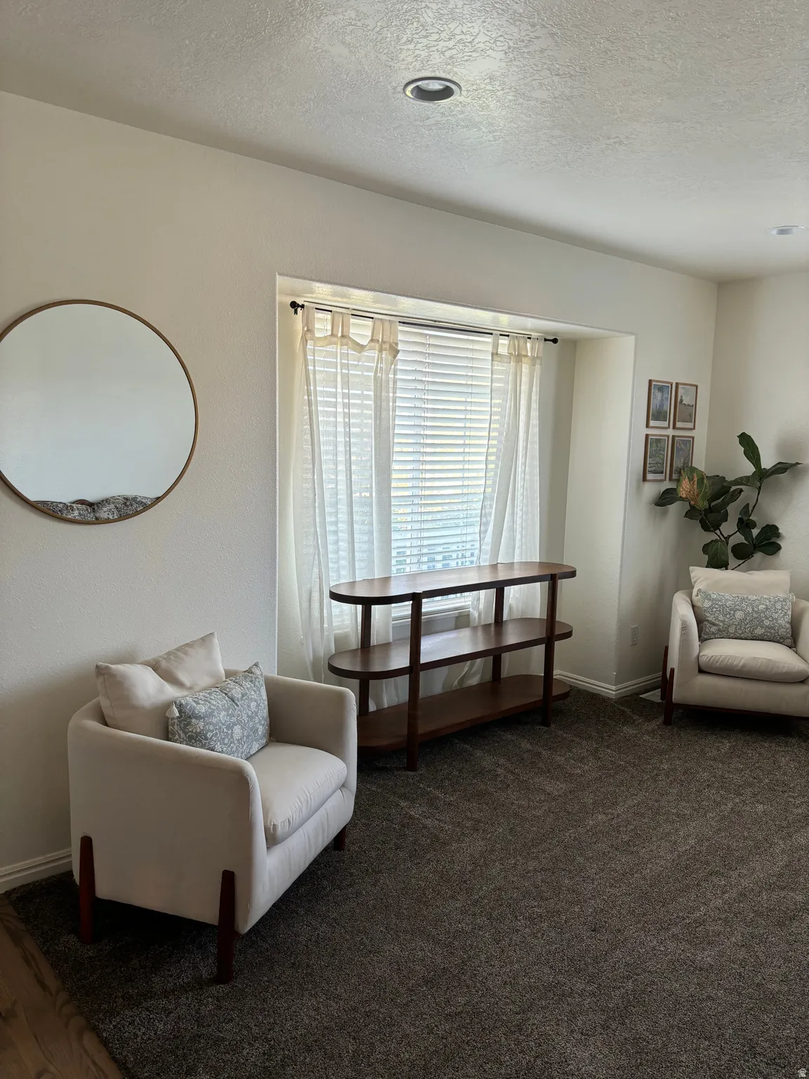 Recessed lighting illuminates a space featuring a large window with blinds and sheer curtains