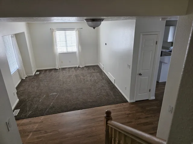 Open living area featuring neutral-toned walls and dark carpeting