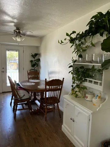 Dining area featuring wood-finish flooring, a ceiling fan with integrated lighting, and a white built-in hutch with shelving