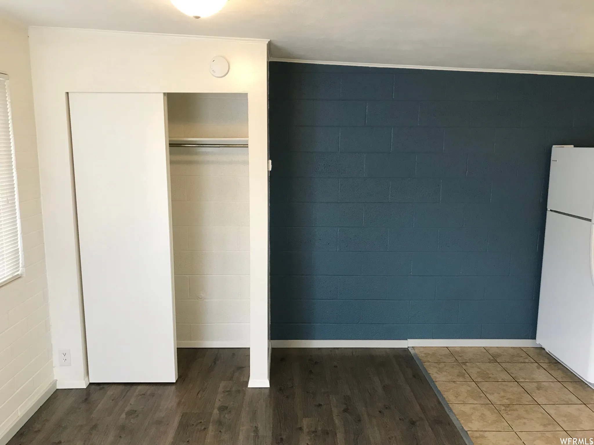 Open wardrobe with a chrome hanging rod and wood-finish flooring