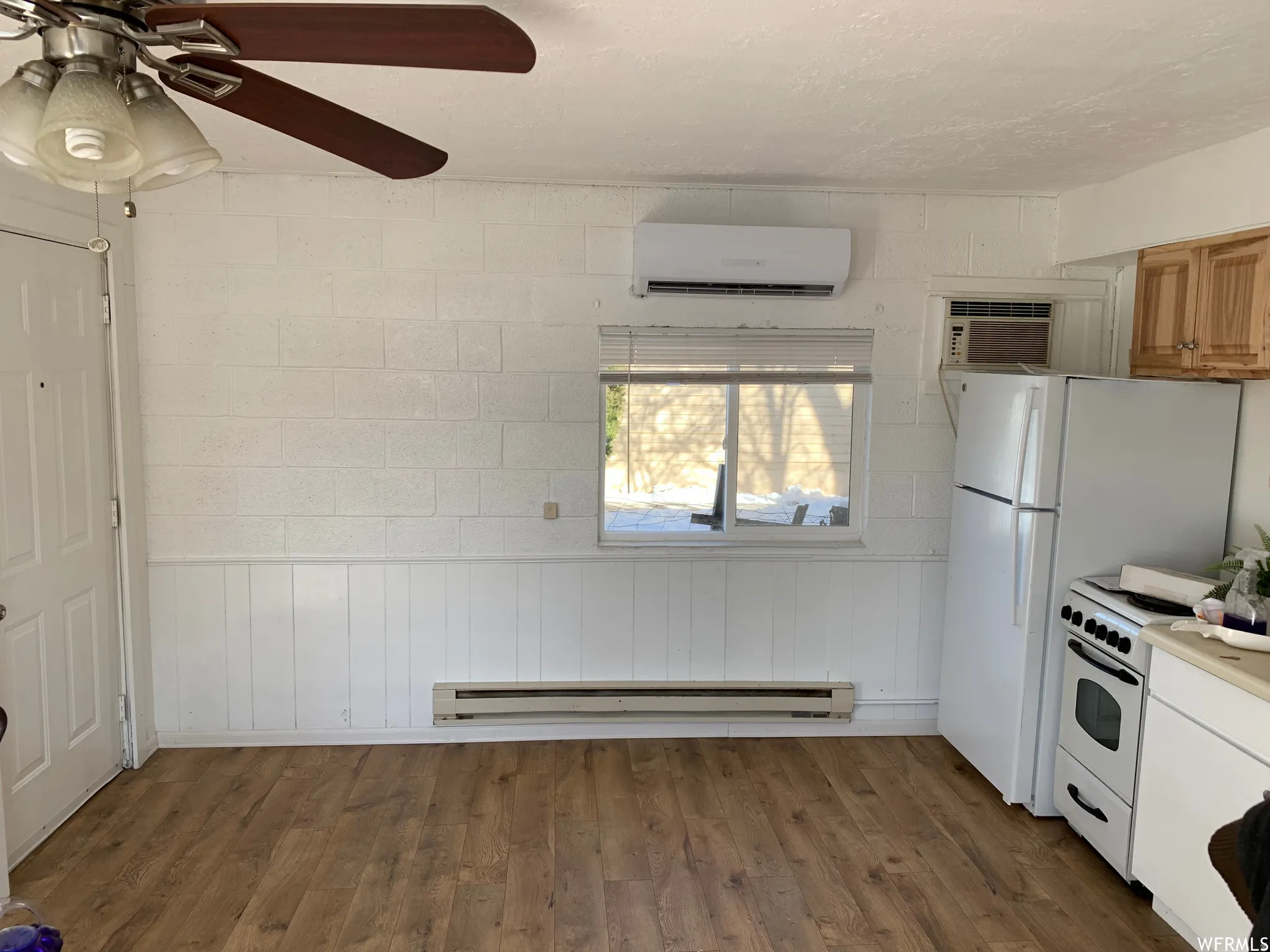 Kitchenette featuring wood-finish flooring, white paneled wainscoting, and a white entry door