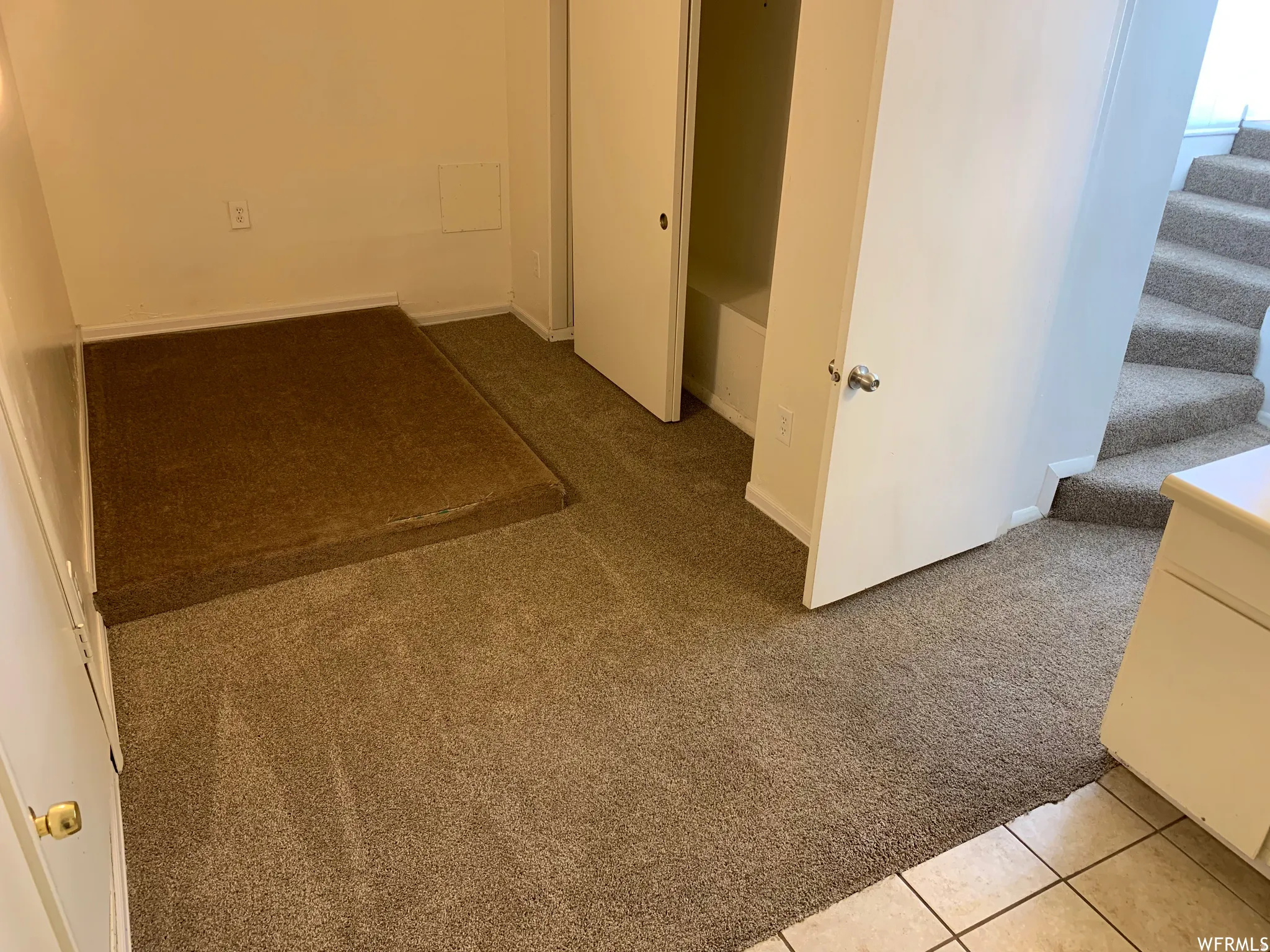Carpeted landing area featuring an integrated storage platform, a built-in closet with bi-fold doors, and neutral wall finishes