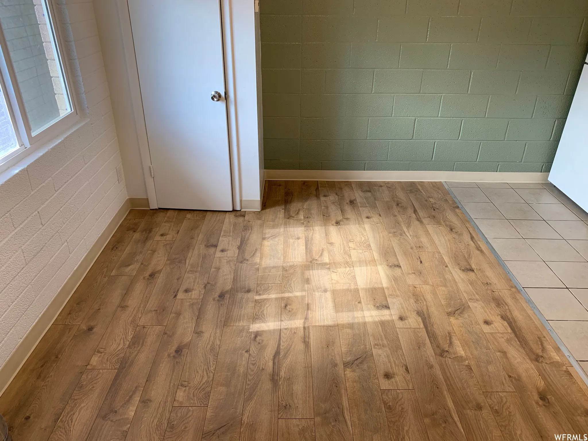 Wood-finish flooring throughout, complemented by a white interior door and a painted block wall