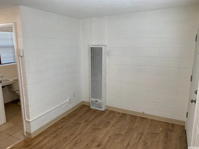 Interior space featuring white painted block walls and wood-finish flooring