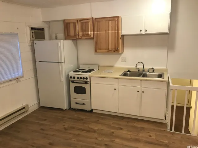 Efficient kitchen space featuring wood-finish flooring, white appliances, a double basin sink, and both wood and white cabinetry